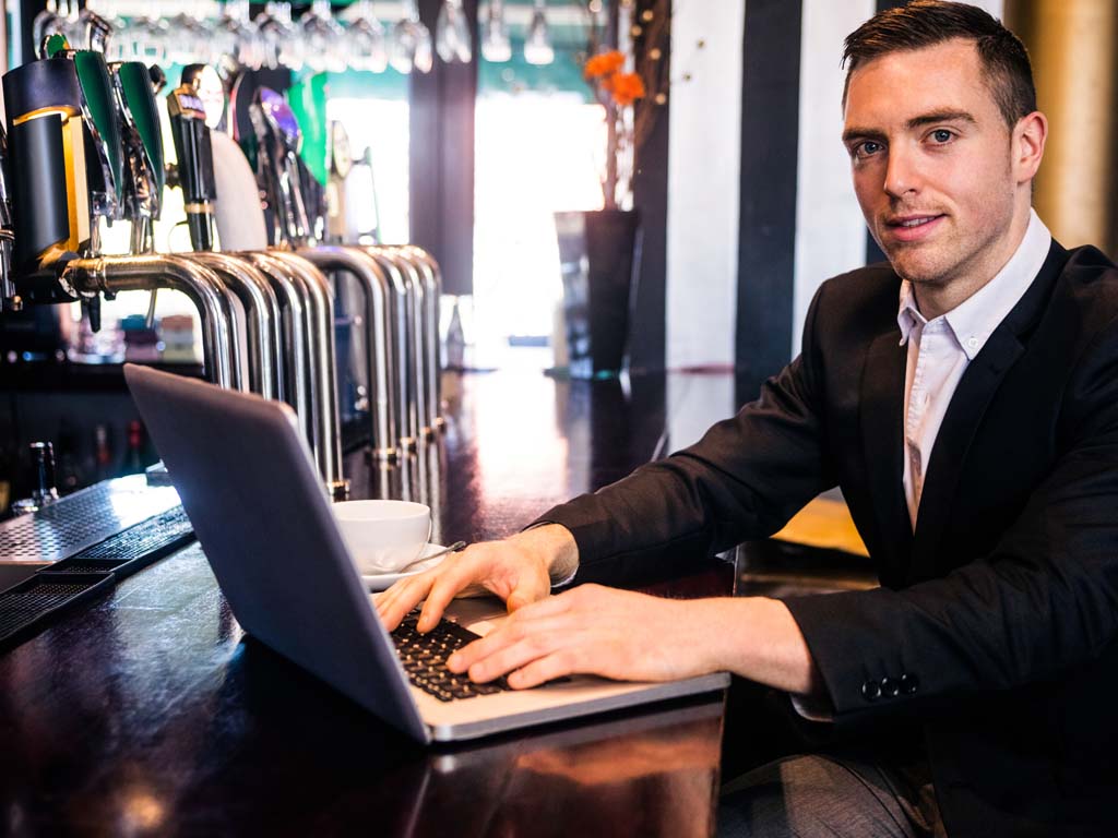 Manager working with laptop on bar top