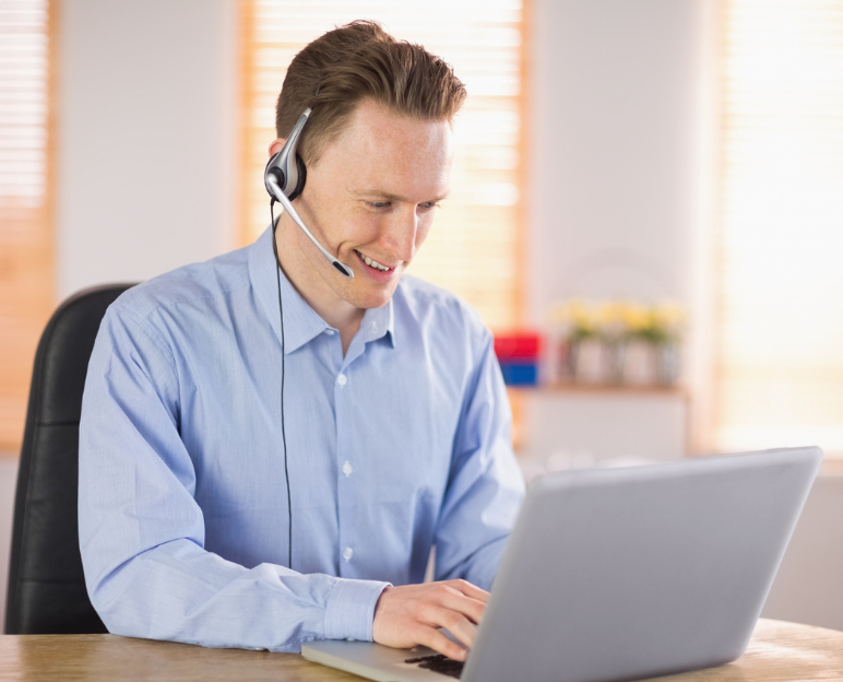 Man working at computer - call centre with headset happy