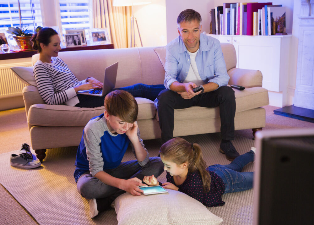 Family watching TV with laptop & tablet